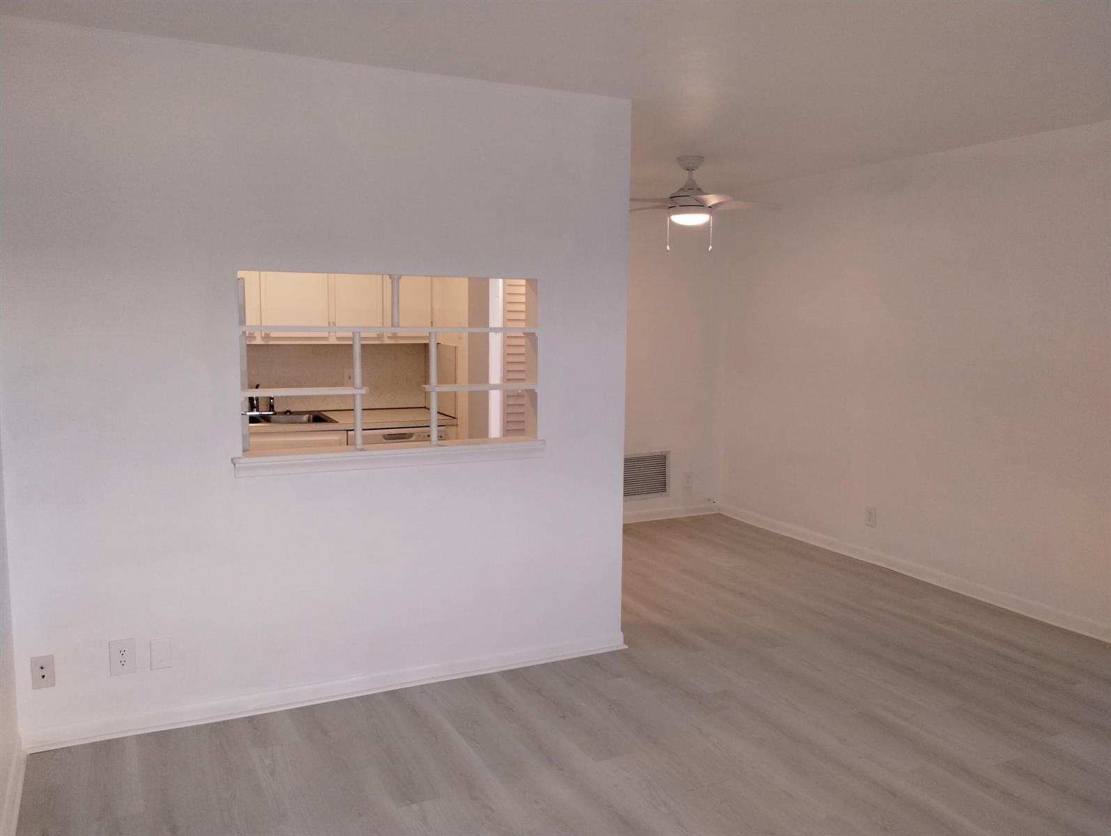 An interior view shows a living area with light wood-look flooring and a kitchen pass-through — 2880 Lake Osborne Drive # 209, FL 33461, FL