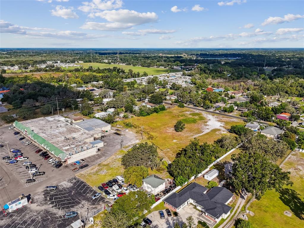 An aerial view shows a commercial building with a parking lot next to vacant land — 3309 GLORIA AVENUE, PLANT CITY, FL