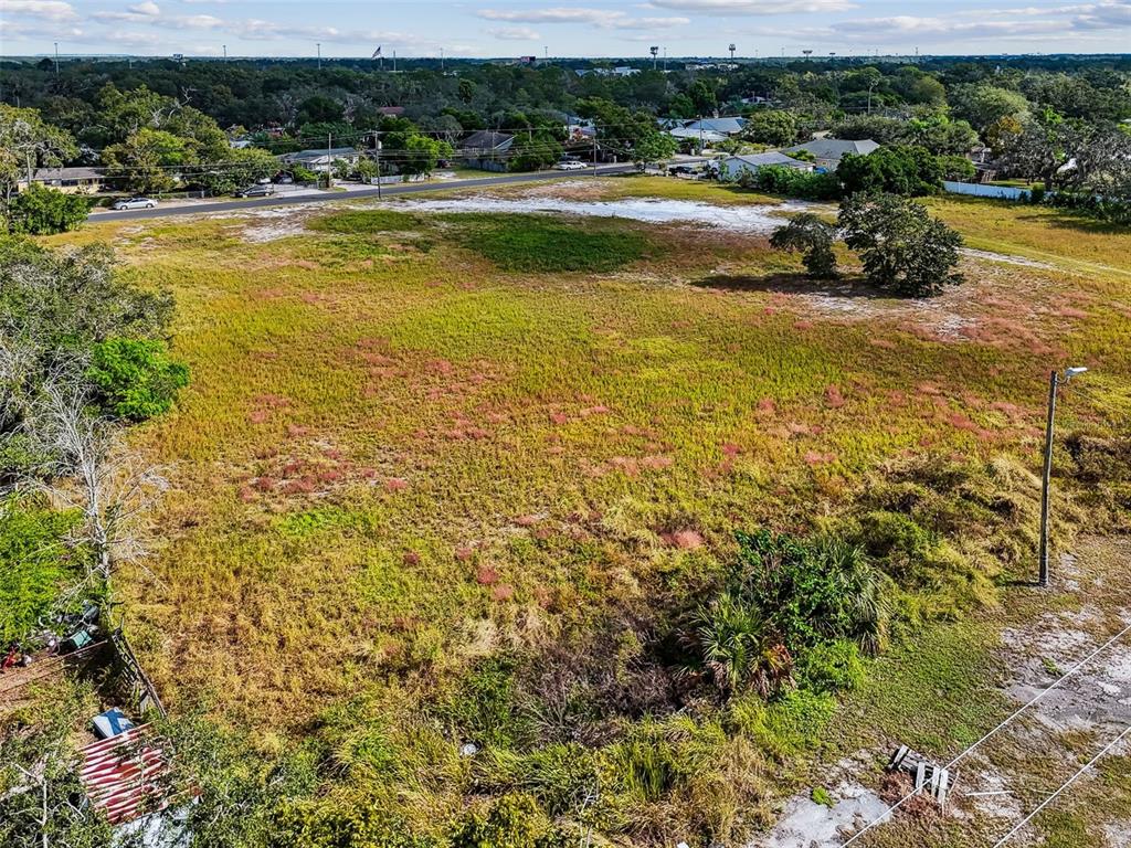 An aerial view shows a large, grassy, undeveloped vacant lot bordering a paved road — 3309 GLORIA AVENUE, PLANT CITY, FL