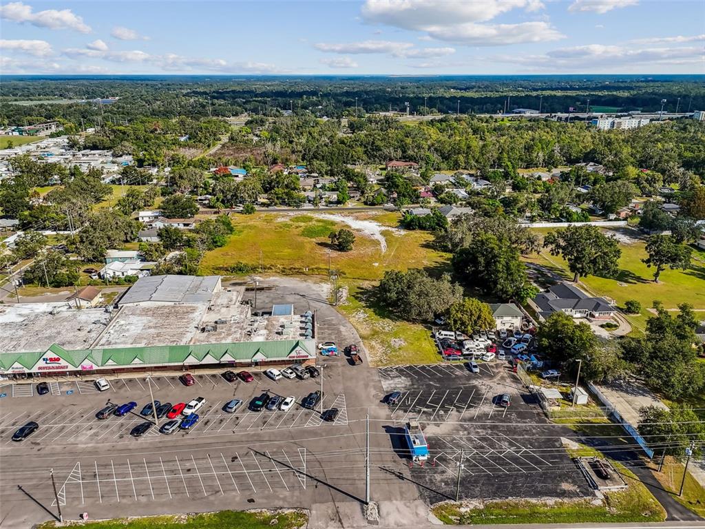 An aerial view shows a commercial building with a parking lot and adjacent vacant land — 3309 GLORIA AVENUE, PLANT CITY, FL