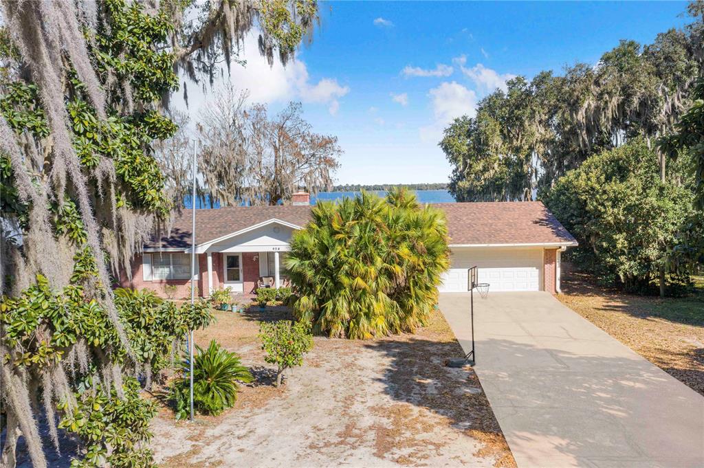 A single-story brick house with a two-car garage sits on a lot near a lake — 436 JEFFERY LANE, HAINES CITY, FL
