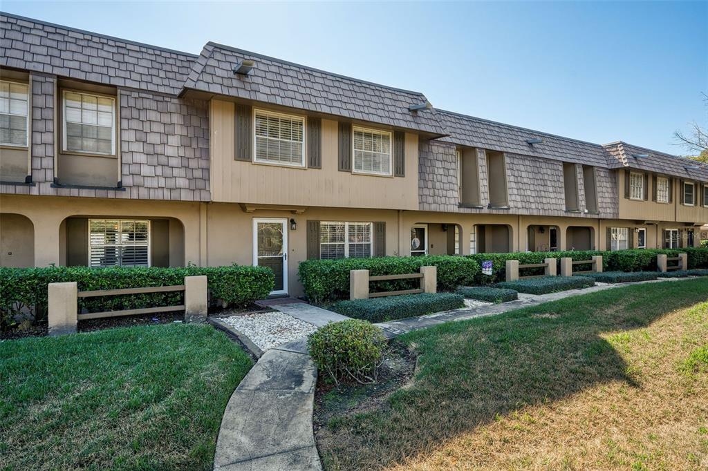 A row of two-story townhouses with brown shingled mansard roofs and manicured hedges — 3104 HARRISON AVENUE UNIT C 18, ORLANDO, FL