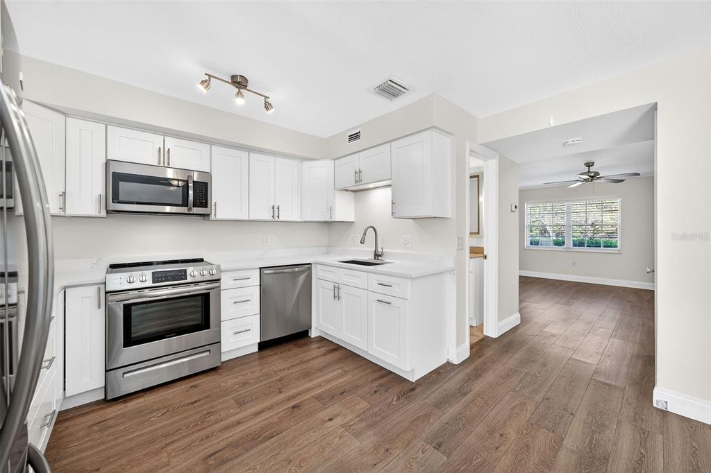 A modern kitchen features white cabinets, stainless steel appliances, and wood-look flooring — 3104 HARRISON AVENUE UNIT C 18, ORLANDO, FL