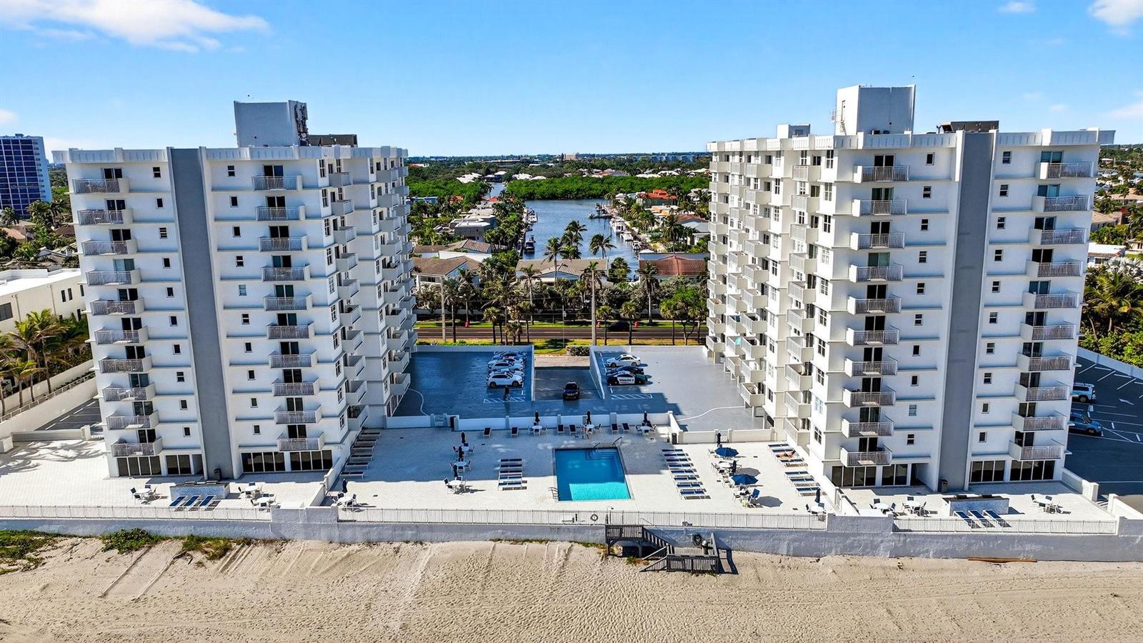 Aerial view of two white multi-story apartment buildings with a shared pool and parking lot — 4505 S Ocean Boulevard # 805, Highland Beach FL 33487, HIGHLAND BEACH, FL