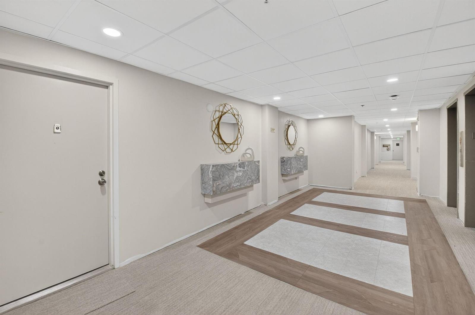 A hallway features a beige door, two wall-mounted marble consoles, and decorative gold mirrors — 4505 S Ocean Boulevard # 805, Highland Beach FL 33487, HIGHLAND BEACH, FL