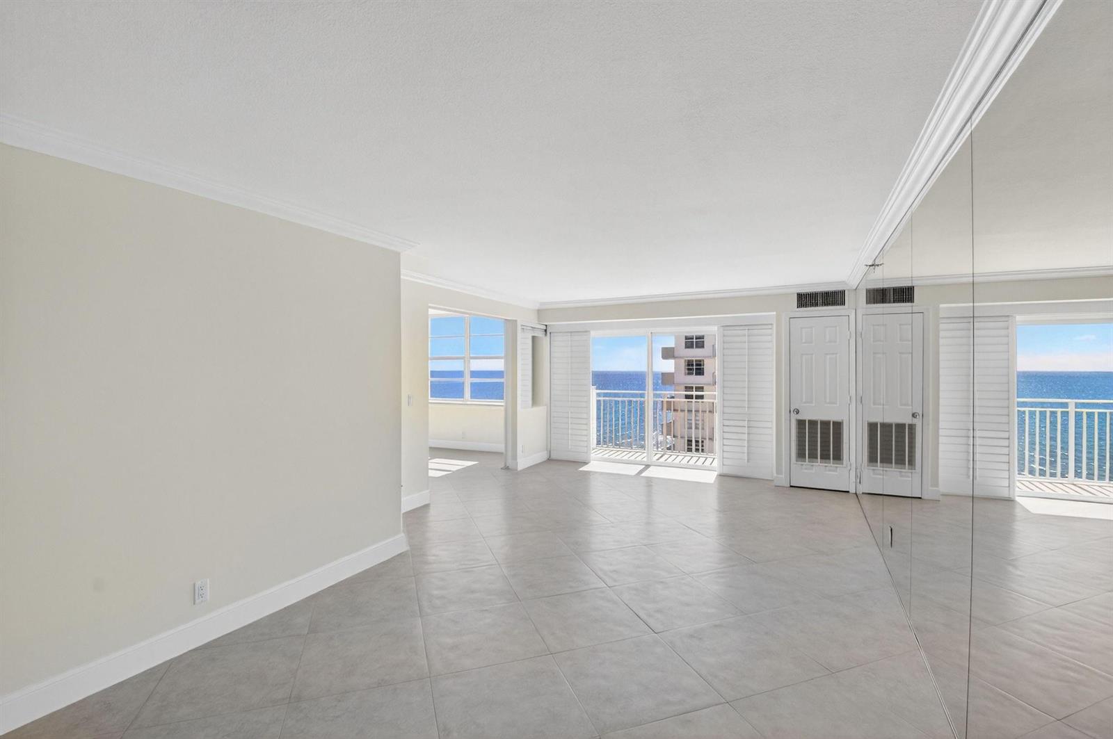 An empty room with light tile floors, mirrored walls, and a balcony overlooking the ocean — 4505 S Ocean Boulevard # 805, Highland Beach FL 33487, HIGHLAND BEACH, FL