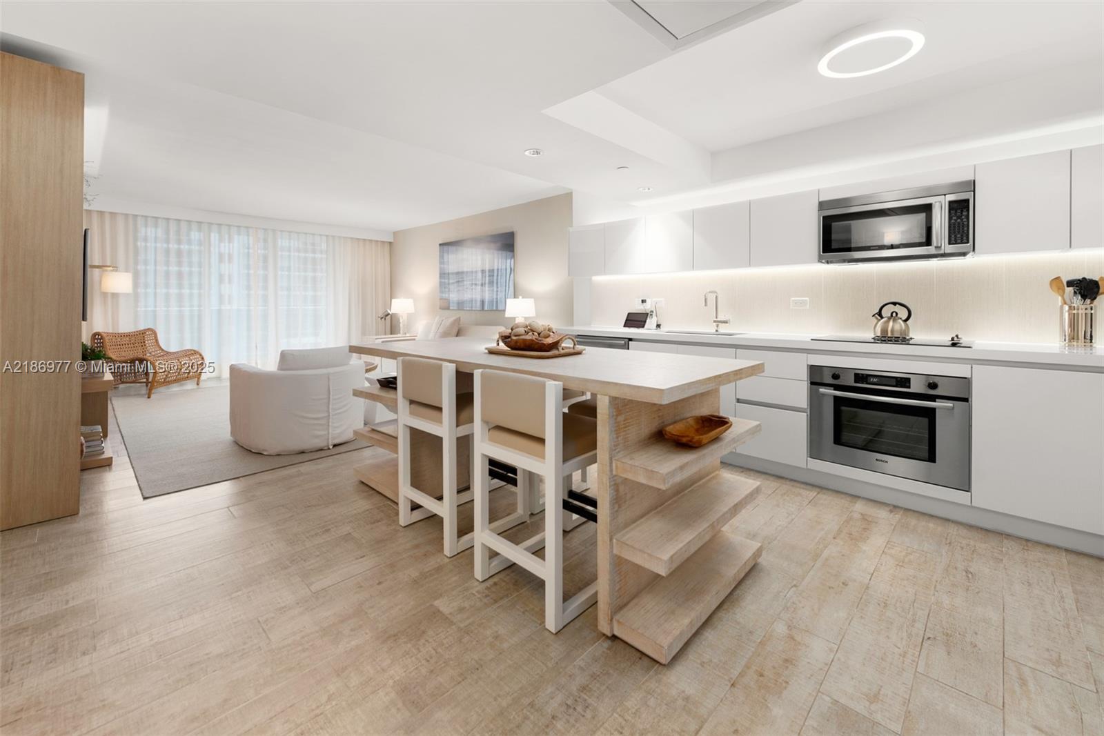 A modern kitchen features a wooden island with bar stools and white cabinetry — 102 24 ST # 1408, Miami Beach FL 33139, MIAMI BEACH, FL