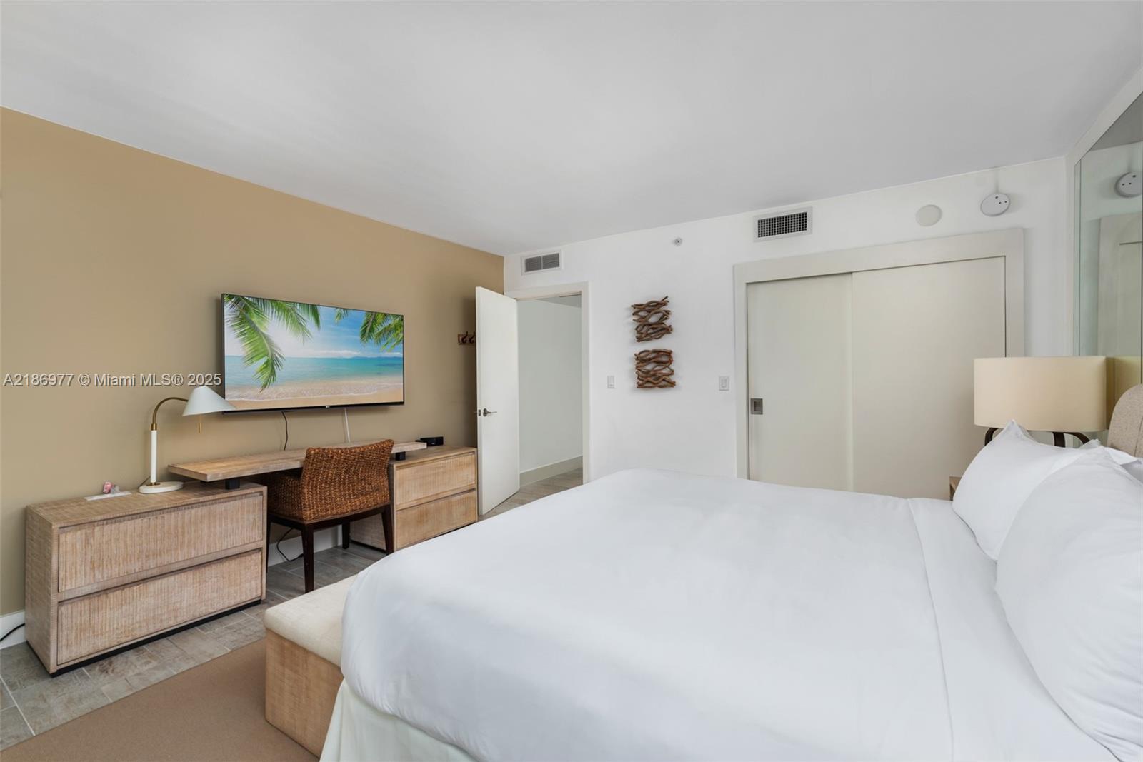 A bedroom features a white bed, a wooden desk with a chair, and a television — 102 24 ST # 1408, Miami Beach FL 33139, MIAMI BEACH, FL