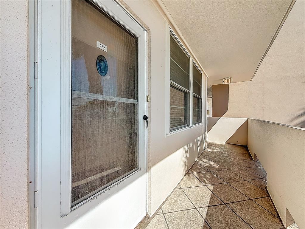 An exterior walkway features a white door labeled 232 and a tiled floor — 7401 BAY ISLAND DRIVE S UNIT 232, SOUTH PASADENA, FL