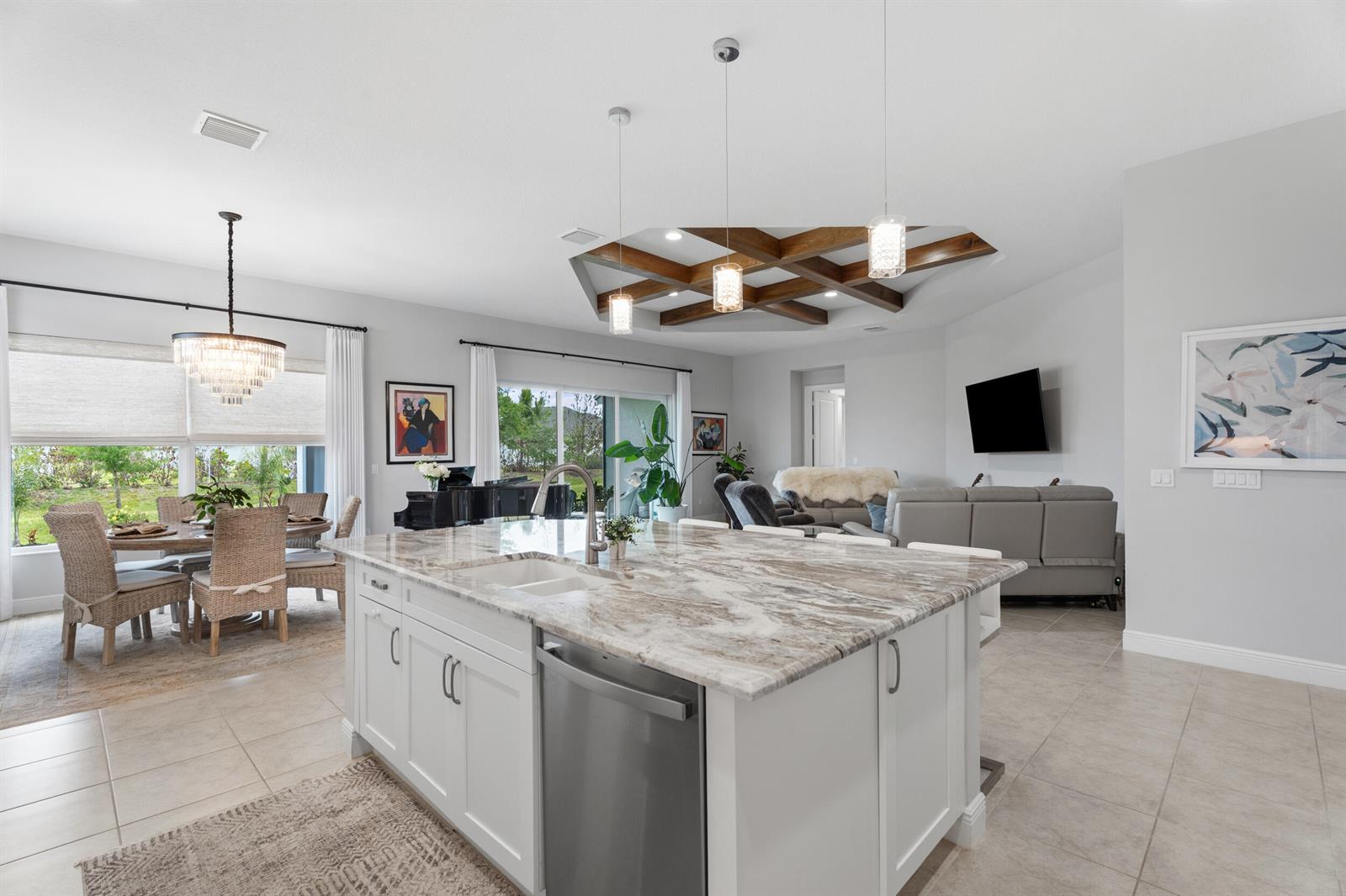 A kitchen island with a stone countertop sits in an open-concept living and dining area — 6390 High Pointe West Way, Vero Beach FL 32967, VERO BEACH, FL
