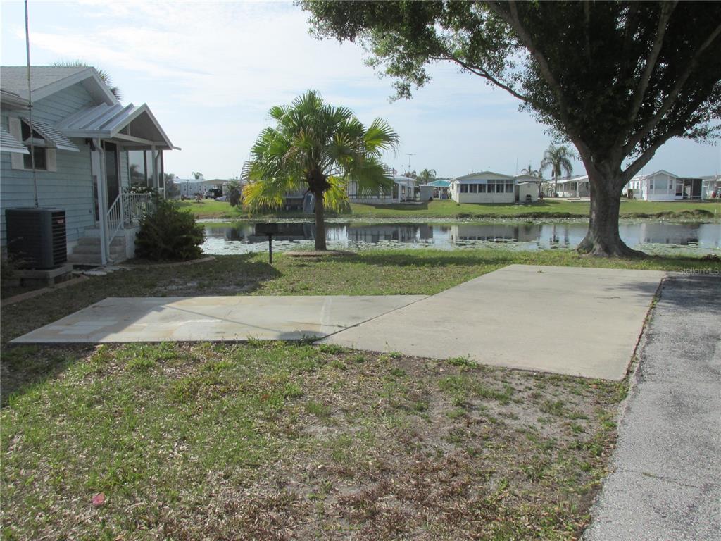 A concrete driveway sits in front of a house overlooking a small pond — 15 RED QUILL CIRCLE, LAKE WALES, FL