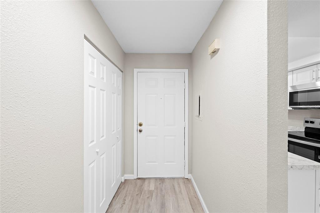 A white entry door sits next to a white closet door in a hallway — 7217 CLOISTER DRIVE UNIT 203, SARASOTA, FL