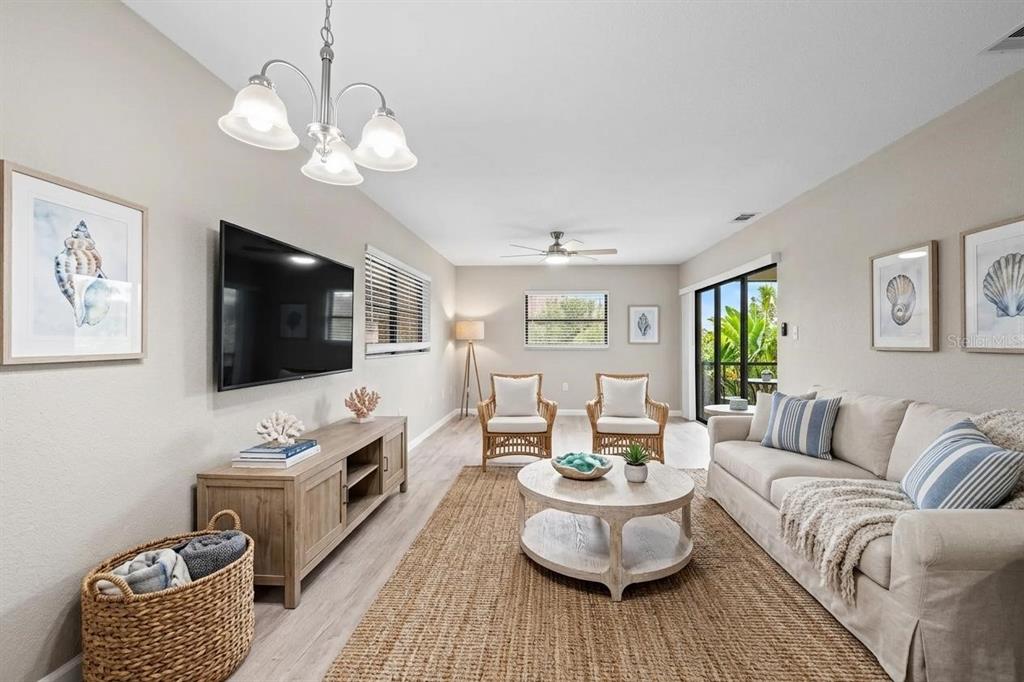A dining area with a wooden table and chairs sits in front of a living room — 7217 CLOISTER DRIVE UNIT 203, SARASOTA, FL