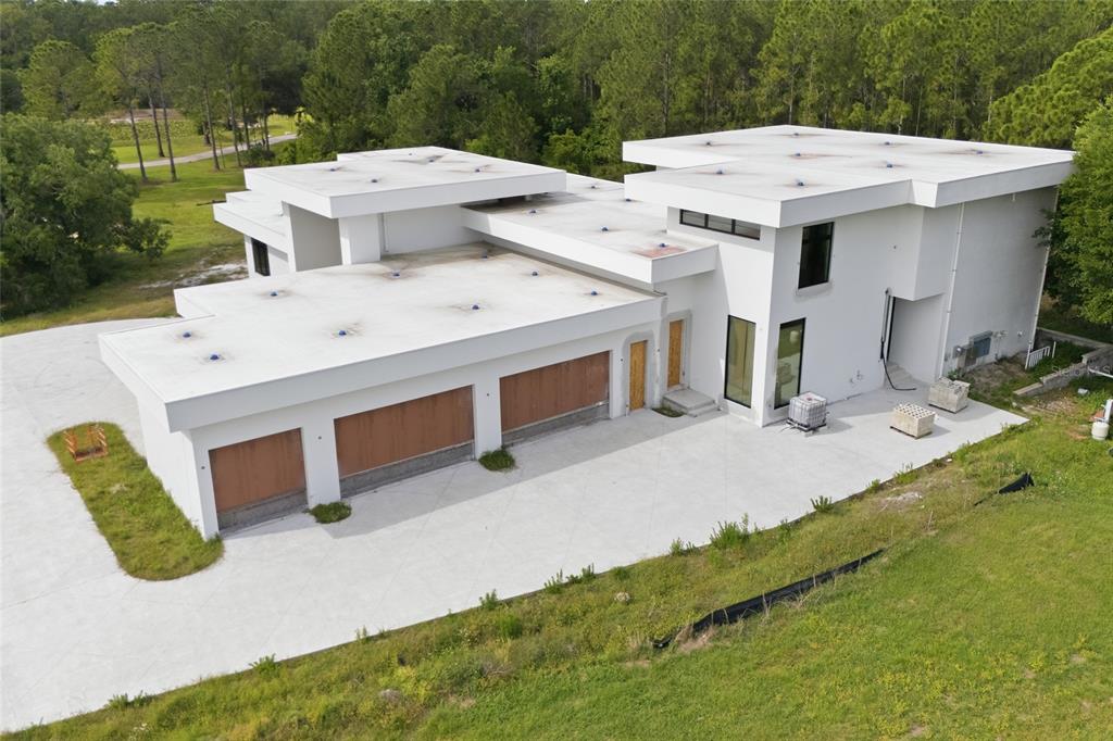 An aerial view of a modern white house under construction with a large concrete driveway — 12505 STONELAKE RANCH BOULEVARD, THONOTOSASSA, FL