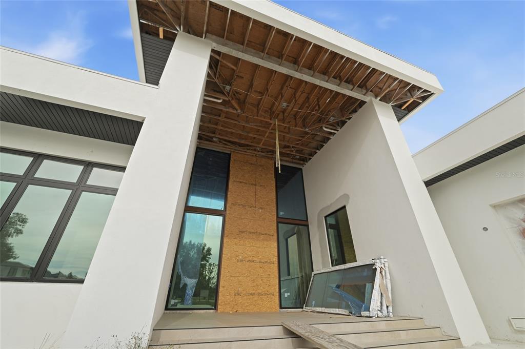 The exterior of a modern home features a large covered entryway with unfinished wood ceilings — 12505 STONELAKE RANCH BOULEVARD, THONOTOSASSA, FL