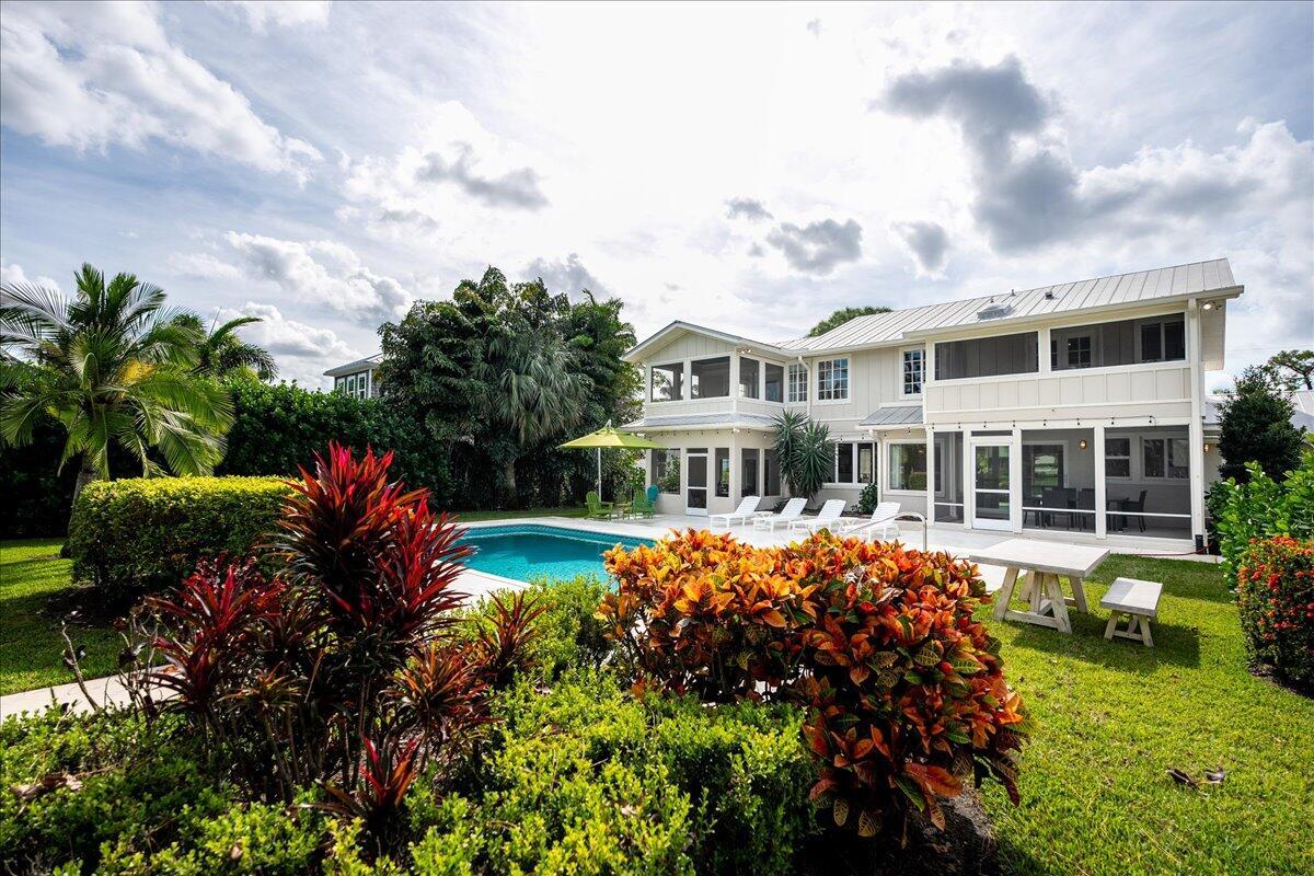 A two-story house with a swimming pool, patio furniture, and lush landscaping in the backyard — 1947 NW Palmetto Terrace, Stuart FL 34994, STUART, FL