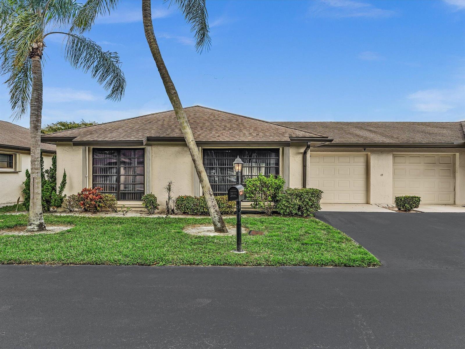 A single-story house with a beige stucco exterior, two garage doors, and a palm tree — 4951 Equestrian Circle # A, Boynton Beach FL 33436, BOYNTON BEACH, FL