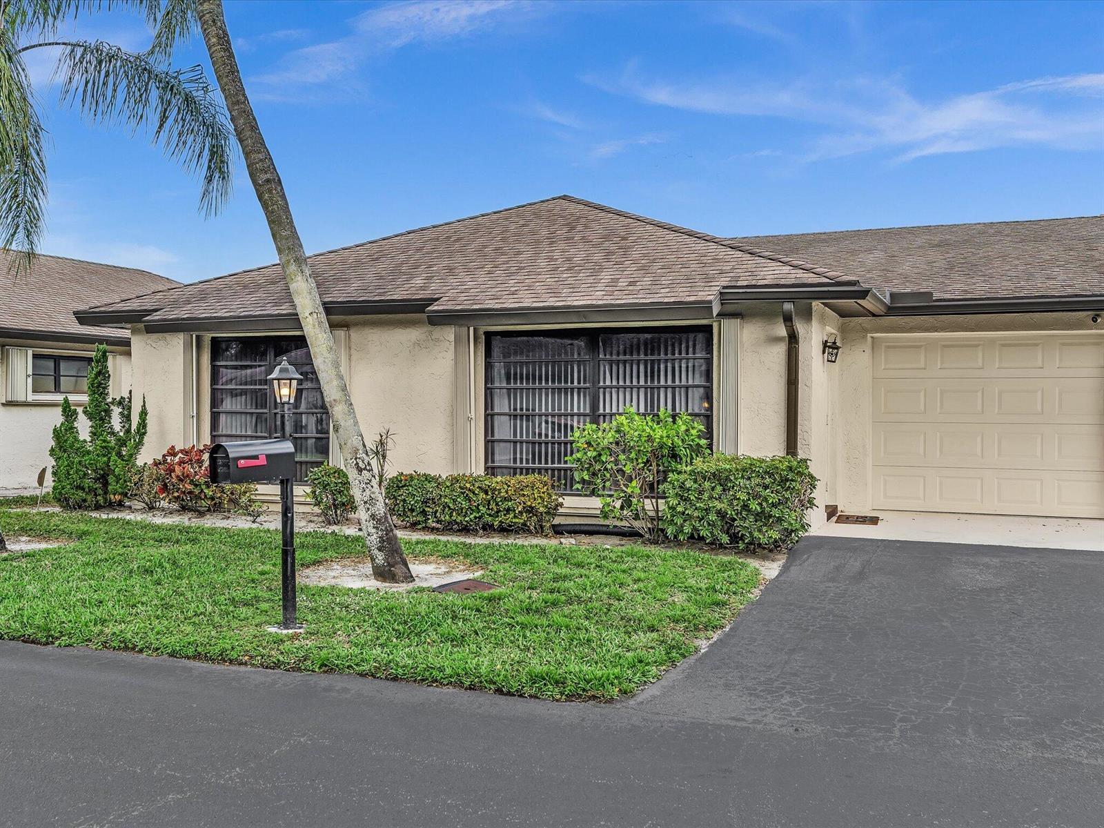 A single-story house with a beige stucco exterior, a garage, and a palm tree — 4951 Equestrian Circle # A, Boynton Beach FL 33436, BOYNTON BEACH, FL