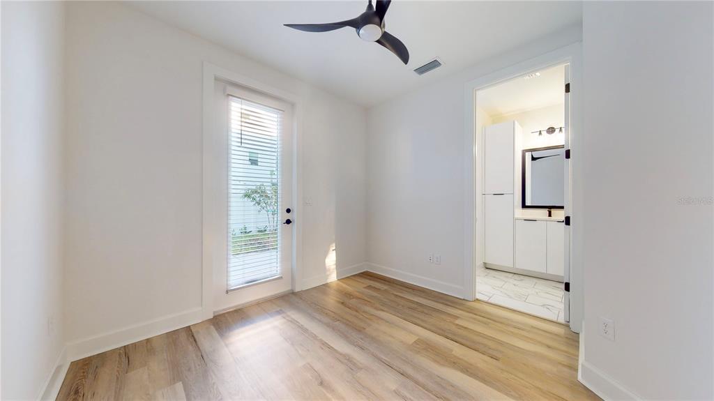 A room with light wood flooring, a ceiling fan, a glass door, and an attached bathroom — 1520 N PIERCE STREET UNIT 5, TAMPA, FL