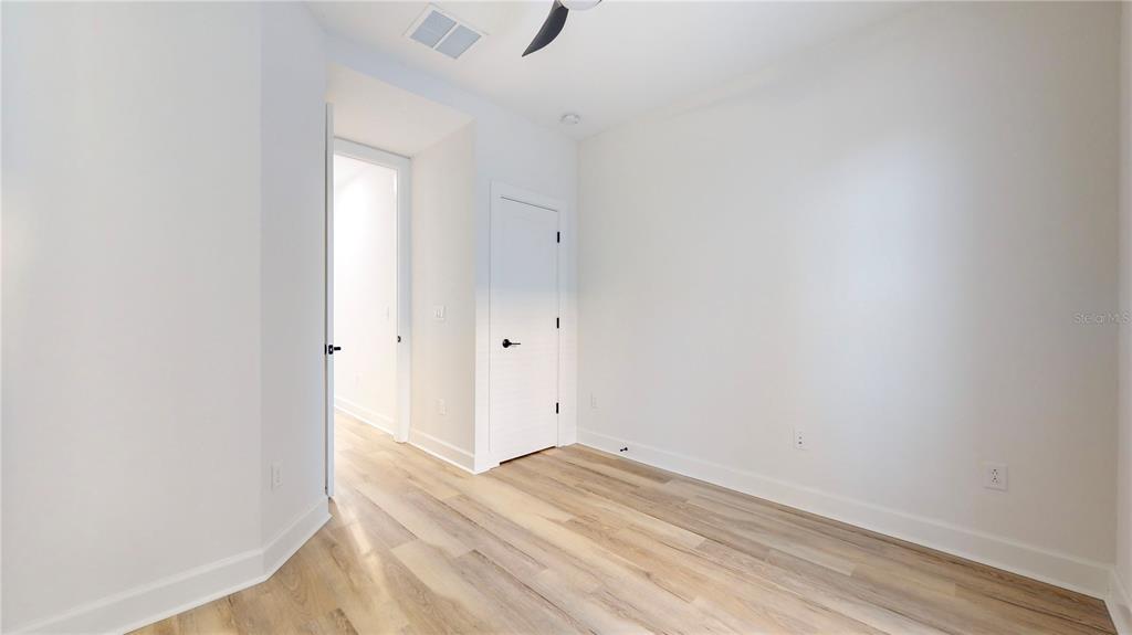 An empty room features light wood-look flooring, white walls, and two closed interior doors — 1520 N PIERCE STREET UNIT 5, TAMPA, FL