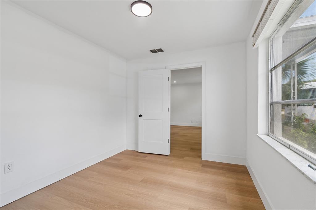 A bright, empty bedroom features white walls, light wood-look flooring, and a single window — 517 HAMPTON AVENUE NE, ST PETERSBURG, FL