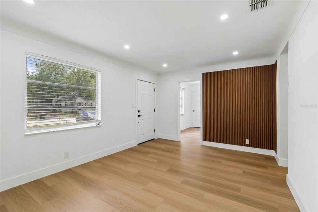 A room with light wood flooring, white walls, a window, and a vertical wood-slat accent wall — 517 HAMPTON AVENUE NE, ST PETERSBURG, FL