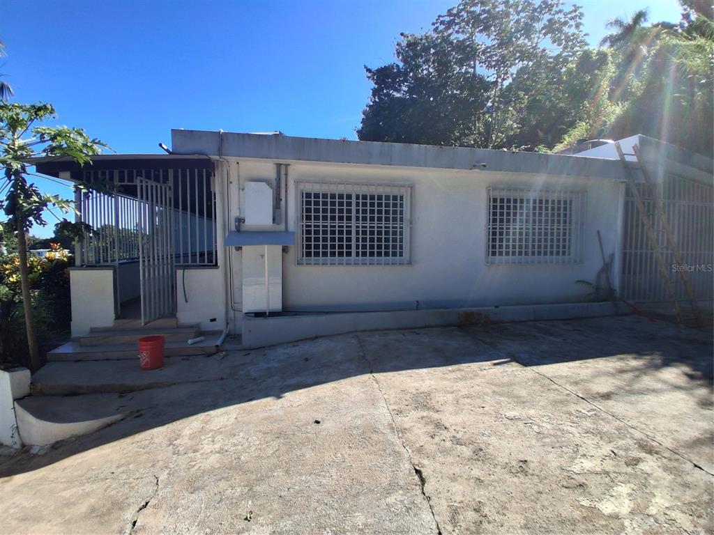 A white concrete house exterior features a gated porch, barred windows, and a cracked driveway — 842 km 8.3 CAIMITO ALTO ST,SECTOR CAMINO PABLO DIAZ, SAN JUAN, PR