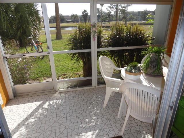 A screened-in patio features white tile flooring, a small dining set, and a golf course view — 3593 Birdie Drive # 103, FL 33467, FL