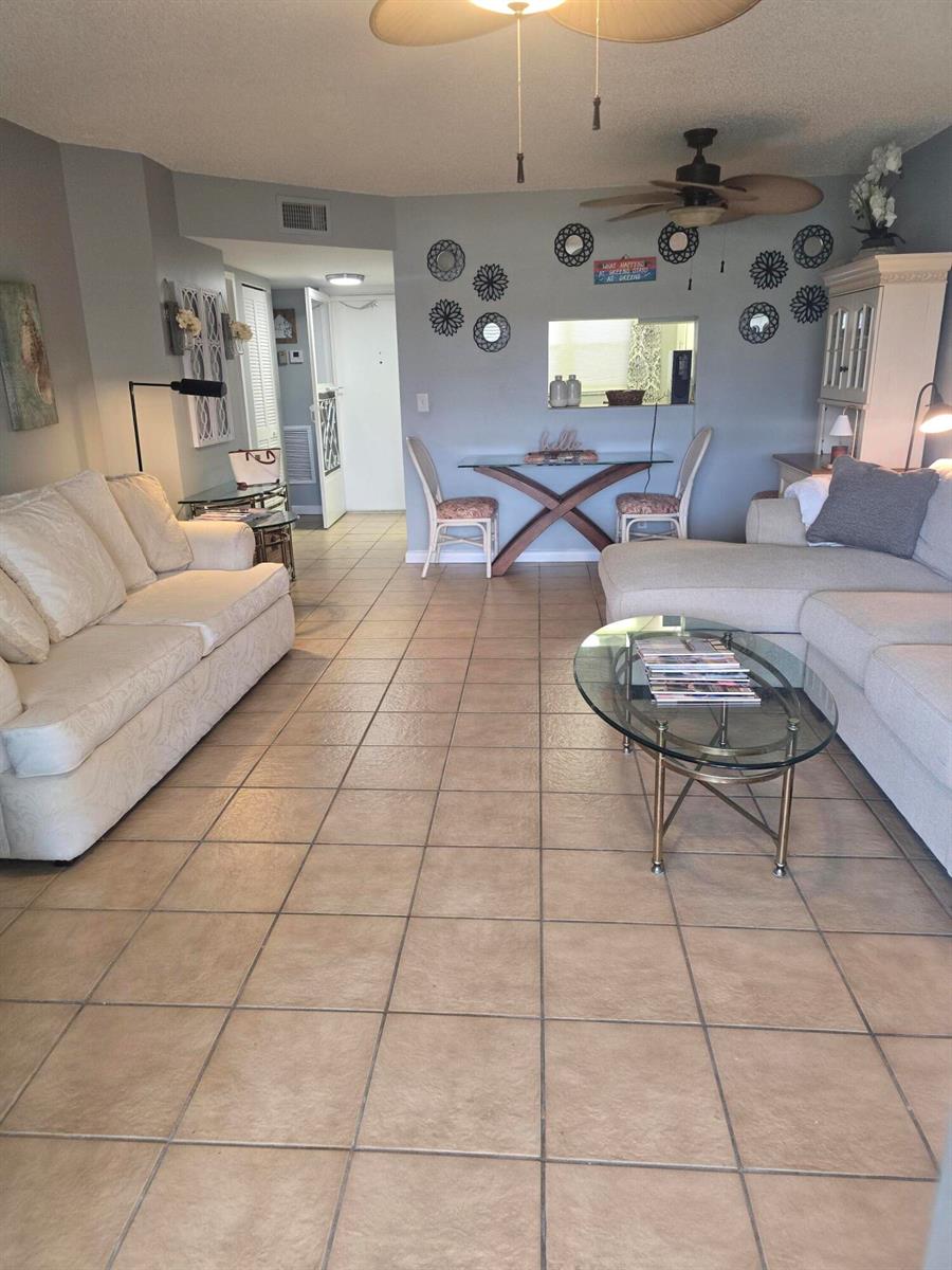 A living room features beige tile flooring, two sofas, a glass coffee table, and dining area — 3593 Birdie Drive # 103, FL 33467, FL