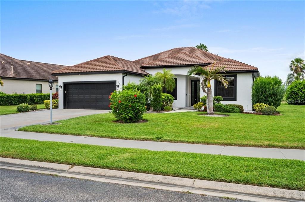 A single-story house with a tile roof, white stucco walls, and a black garage door — 1835 BOBCAT TRAIL, NORTH PORT, FL