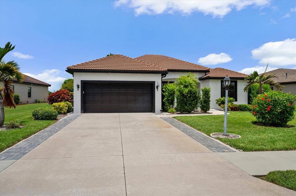 A single-story house with a brown tile roof, white stucco walls, and a two-car garage — 1835 BOBCAT TRAIL, NORTH PORT, FL