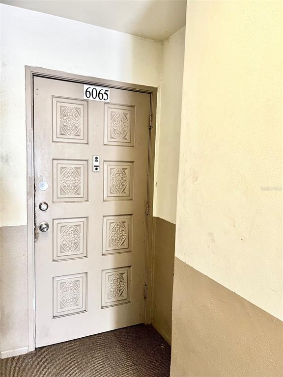 A beige door with six decorative panels and the number 6065 is set in a hallway — 6065 VILLAGE CIRCLE UNIT 6065, ORLANDO, FL