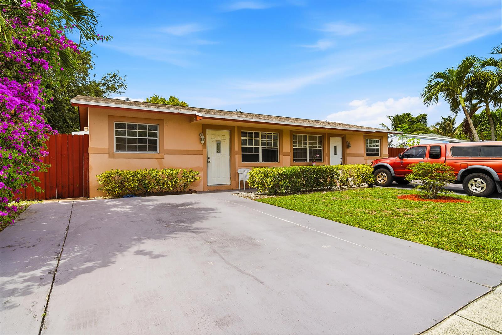 A single-story peach-colored house with a concrete driveway, a red truck, and blooming bougainvillea — 550 NE 37th Street # 2, Pompano Beach FL 33064, POMPANO BEACH, FL