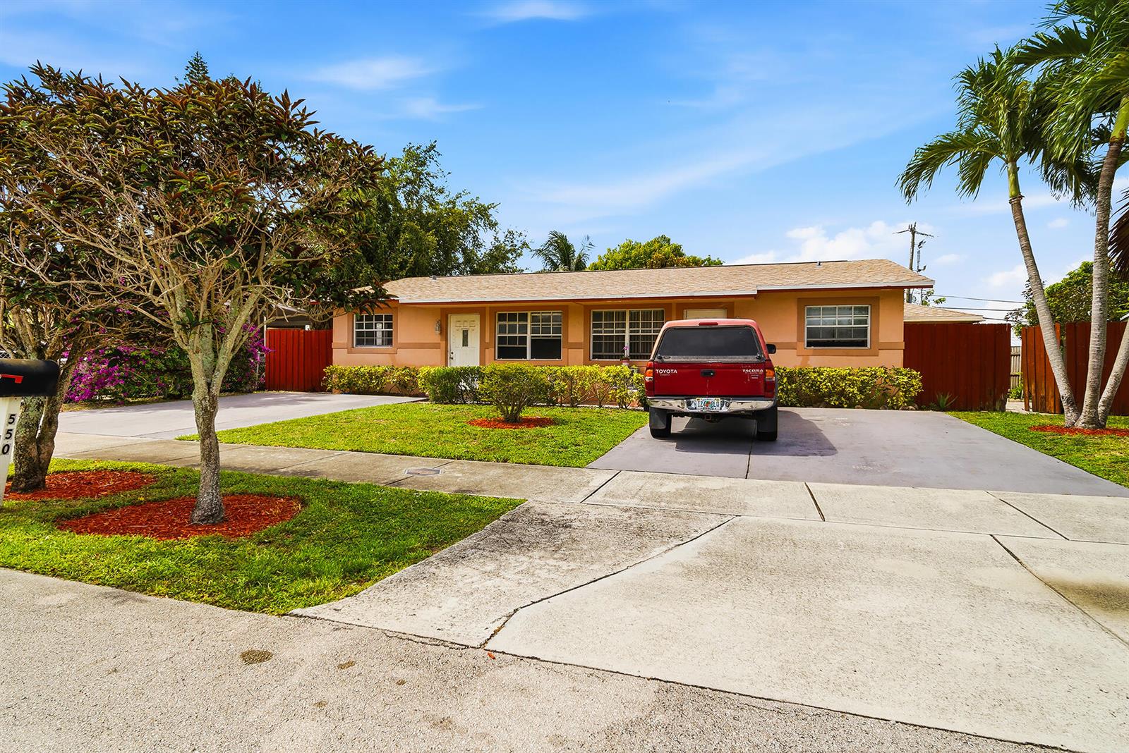 A single-story house with a peach exterior, a concrete driveway, and a red pickup truck — 550 NE 37th Street # 2, Pompano Beach FL 33064, POMPANO BEACH, FL