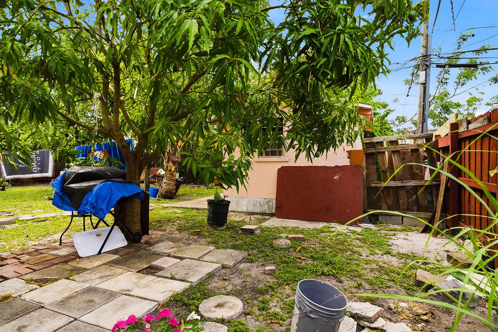 A backyard features a tree, a small shed, a blue-covered grill, and paved stones — 550 NE 37th Street # 2, Pompano Beach FL 33064, POMPANO BEACH, FL