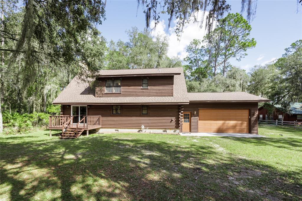 A two-story log cabin home with a brown shingle roof and an attached two-car garage — 239 RILEY LAKE DRIVE, HAWTHORNE, FL