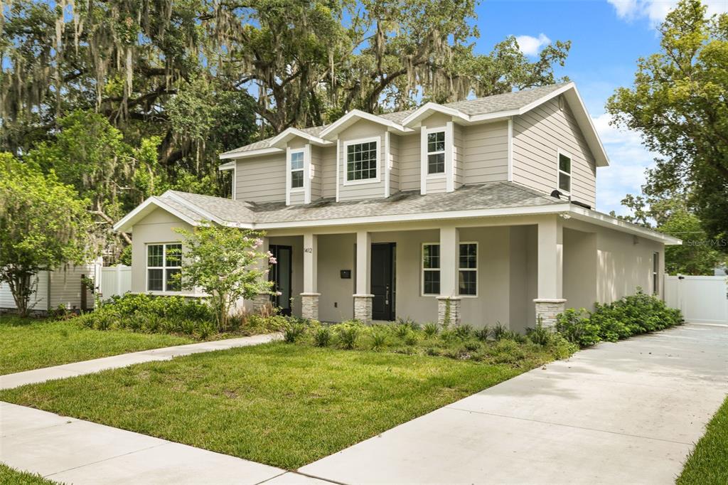 A two-story house with light tan siding, a covered front porch, and a concrete driveway — 1412 W HARVARD STREET, ORLANDO, FL