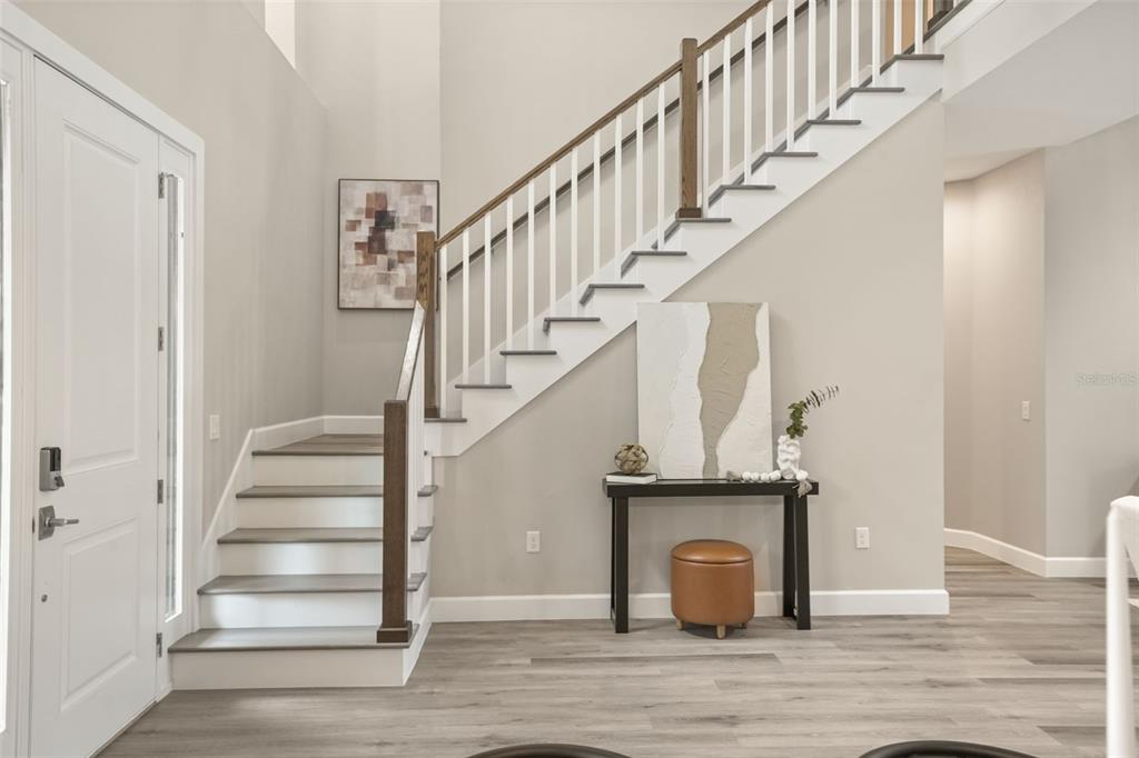 An entryway features a staircase with white railings, wood treads, and a console table below — 1412 W HARVARD STREET, ORLANDO, FL