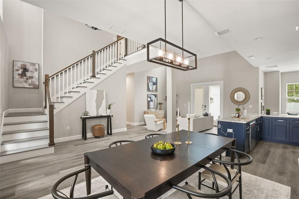 A dining area with a dark wood table sits before a staircase and open kitchen — 1412 W HARVARD STREET, ORLANDO, FL