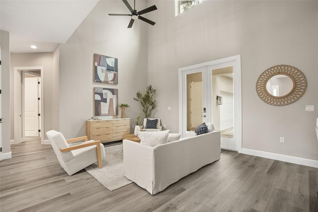 A living room features light wood floors, a high ceiling, a sofa, and two armchairs — 1412 W HARVARD STREET, ORLANDO, FL