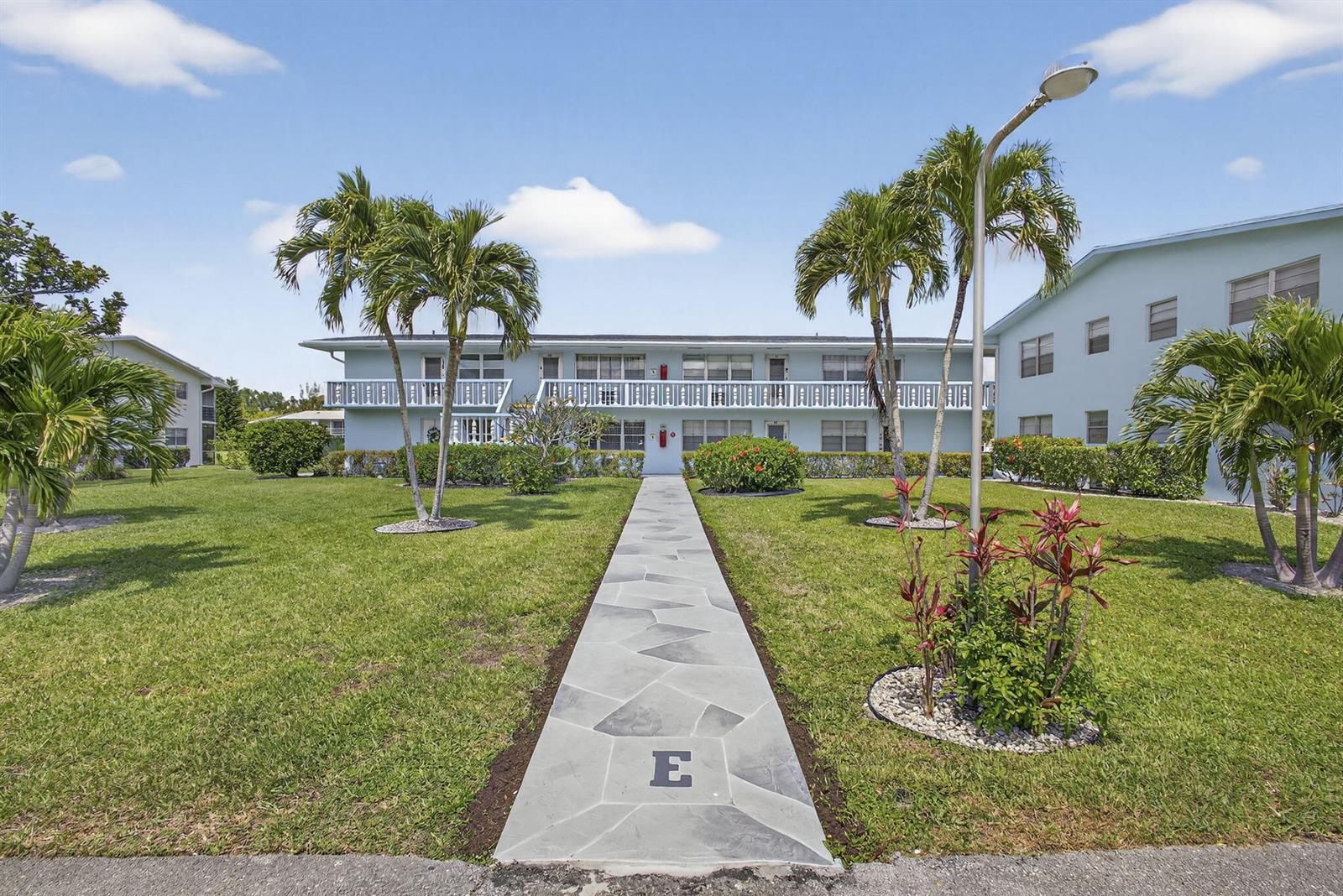 A stone walkway leads to the entrance of a two-story apartment building with palm trees — 106 E Camden E, West Palm Beach FL 33417, WEST PALM BEACH, FL