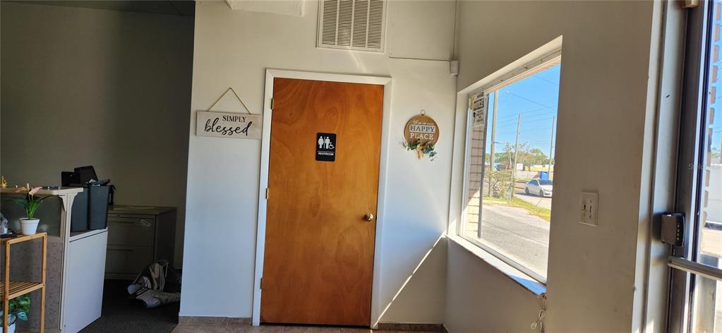 An interior view shows a wooden restroom door, a window, and office furniture — 610 N COMBEE ROAD, LAKELAND, FL