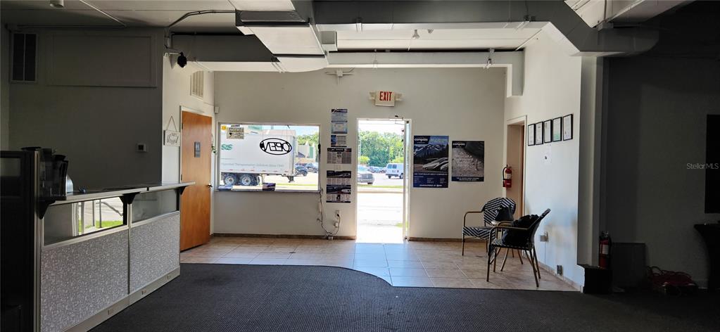 An office lobby features a reception desk, tiled and carpeted flooring, and an exit door — 610 N COMBEE ROAD, LAKELAND, FL