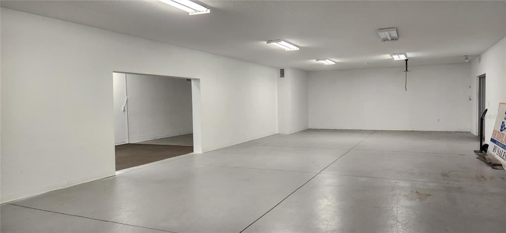 An empty, white-walled commercial space features a concrete floor and several overhead fluorescent lights — 610 N COMBEE ROAD, LAKELAND, FL