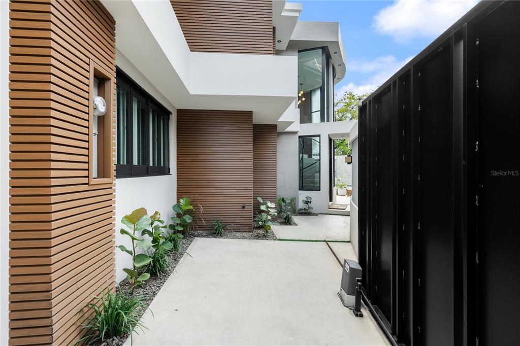 A modern exterior features horizontal wood siding, concrete flooring, and a black metal gate — 1 ALMENDARES, SAN JUAN, PR