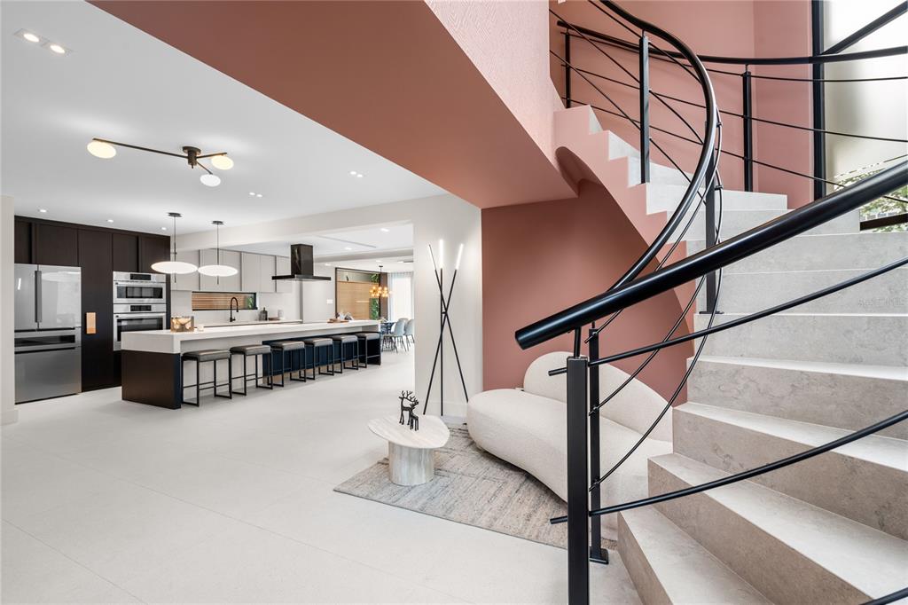 A modern kitchen and living area feature a curved staircase with black metal railings — 1 ALMENDARES, SAN JUAN, PR