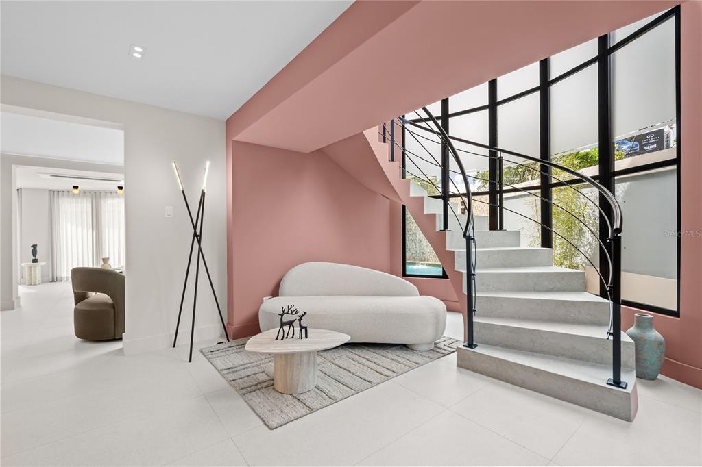 A modern living area features a curved white sofa, a staircase, and pink accent walls — 1 ALMENDARES, SAN JUAN, PR