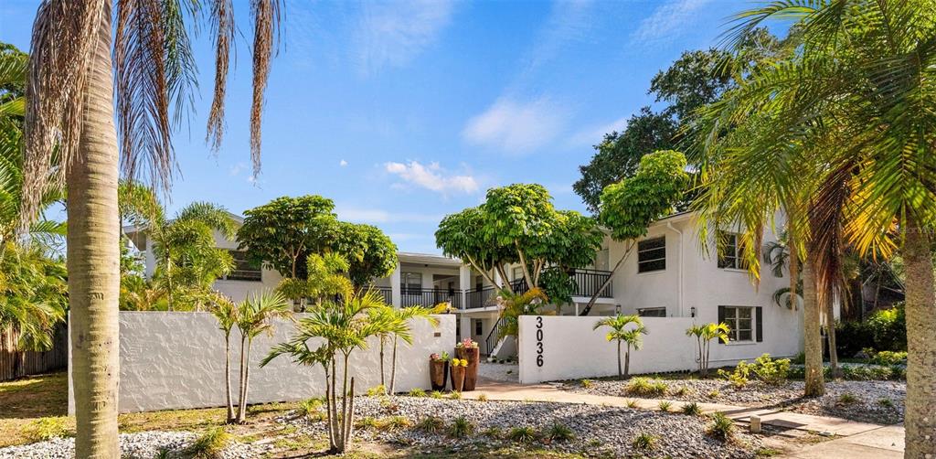 A two-story white apartment building features palm trees and a low wall in front — 3036 6TH AVENUE N, ST PETERSBURG, FL