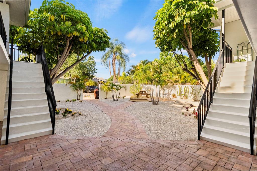 An outdoor courtyard features a brick paver path between two staircases leading to upper levels — 3036 6TH AVENUE N, ST PETERSBURG, FL
