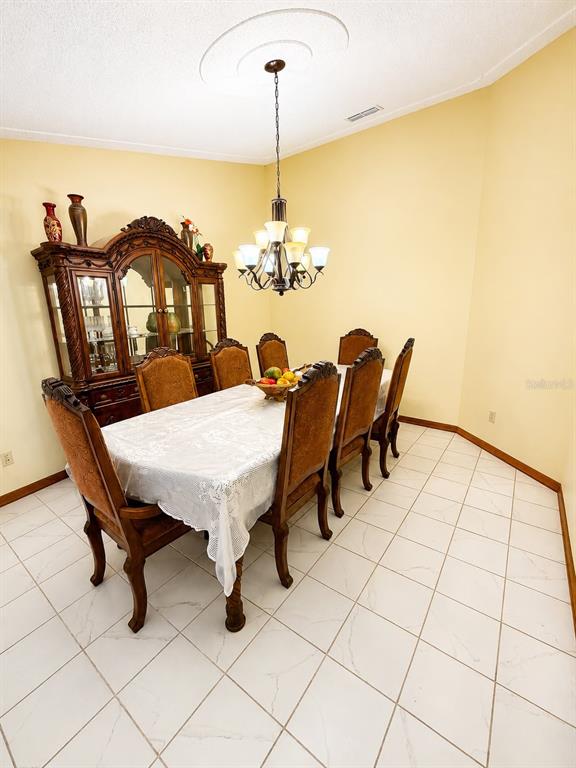 A dining room features a wooden hutch, a table with six chairs, and a chandelier — 13506 SW 43RD CIRCLE SW, OCALA, FL